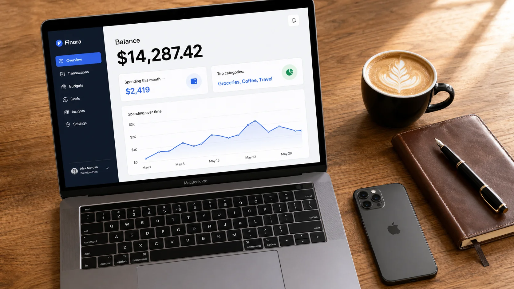 Photoreal flat-lay of MacBook Pro showing a fintech dashboard with sharp readable typography on a wooden desk